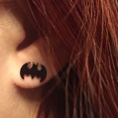 a woman with red hair and piercings on her ear is wearing a bat shaped nose ring