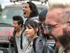 a group of people standing next to each other in front of a truck with their mouths open