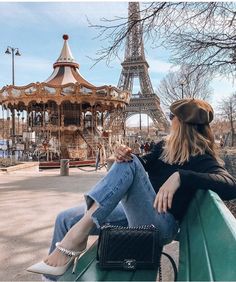 a woman sitting on top of a green bench next to the eiffel tower