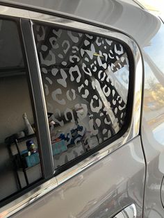 the side window of a silver car with black and white designs on it