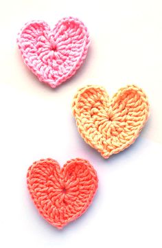 three crocheted hearts sitting on top of a white table next to each other