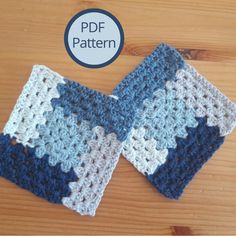 two blue and white crocheted squares sitting on top of a wooden table