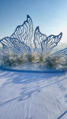 an artistic sculpture is shown in the middle of a snow covered field with trees and bushes