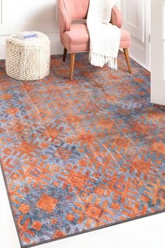 an orange and blue area rug in a living room with a pink chair next to it