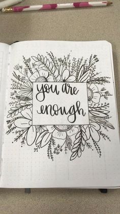 an open notebook with the words you are enough written in black ink on it and surrounded by flowers