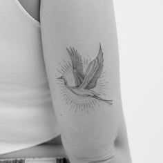 a woman's arm with a bird tattoo on it