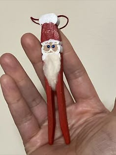 a hand holding a red and white santa clause doll