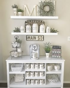 a white shelf with coffee cups and mugs on it in front of a sign that says main st