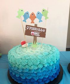 there is a cake with blue frosting and two fish on top that says otshally one