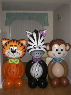 three inflatable animal balloons are sitting on the floor next to an orange and black balloon