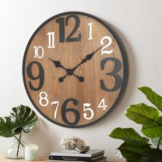 a clock that is on the wall next to a potted plant and some books