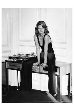 a black and white photo of a woman sitting at a table with chess pieces on it