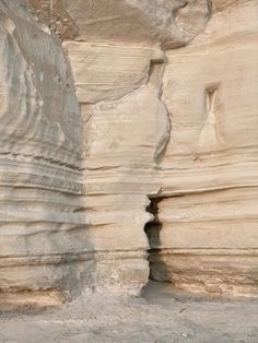 a man standing in front of a large rock formation with an open hole at the top