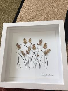 an image of some flowers in a white frame on the floor with carpet behind it