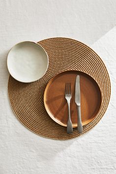 a place setting with silverware on a woven place mat