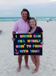 two people standing on the beach holding a sign that says shore can sea mysel gon to prom with you