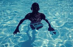 a person in the water with a frisbee under their arm and feet,