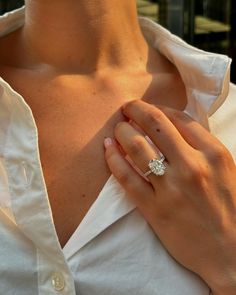 a close up of a person wearing a ring on their left hand and holding onto her shirt