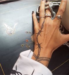 a woman's hand with barbed wire tattooed on her left wrist and the other hand holding a chain