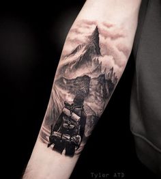 a man's arm with a mountain and backpack tattoo on the left upper arm