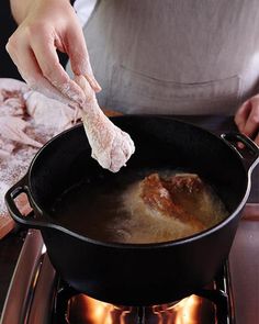 a person is cooking some food in a pot on the burner with one hand