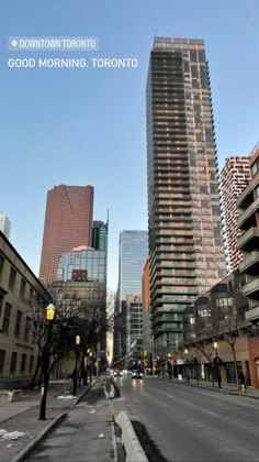 an empty city street with tall buildings in the back ground and snow on the ground