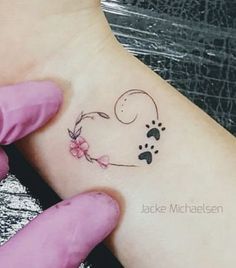 a person with a tattoo on their arm holding a small dog's paw in the shape of a heart