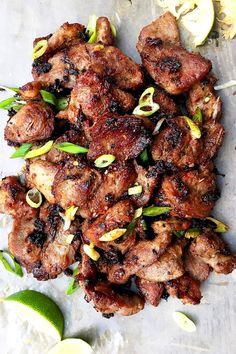 chicken skewers with lemon wedges and green onions on a sheet of parchment paper