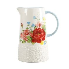 a white pitcher with red and blue flowers painted on the side, sitting against a white background