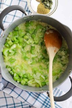 a wooden spoon in a pot filled with green vegetables