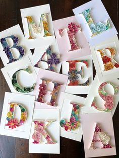 the letters are made up of different types of paper flowers and ribbons on top of each letter