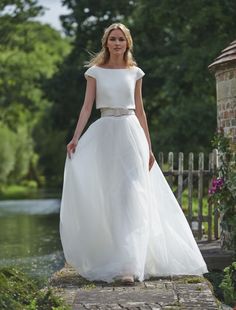 a woman in a white dress is walking down the street with her hand on her hip