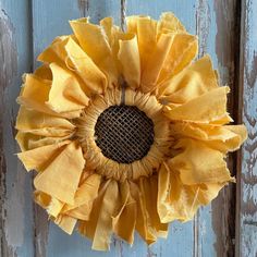 a yellow flower is hanging on the side of a wooden door with peeling paint and grunge