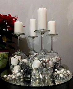 a table topped with two wine glasses filled with white candles and ornaments next to a potted plant