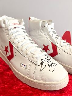 a pair of white and red sneakers with autographed stars on the soles