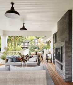 an outdoor living area with white wicker furniture and wood flooring on the porch