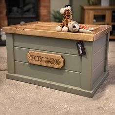 a toy box with a stuffed giraffe sitting on it's top and the word toy box written in wood