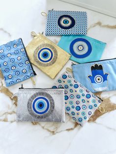 five small pouches with evil eye designs on them sitting on a marble countertop