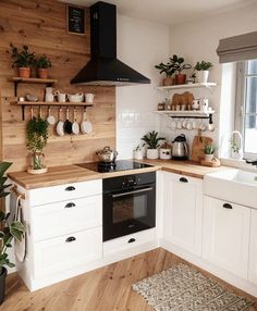 a kitchen with white cabinets and wooden shelves filled with potted plants on the wall