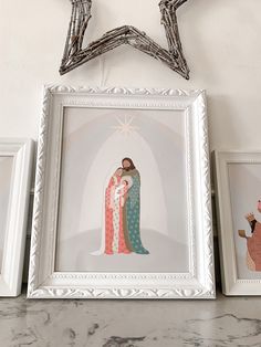 three framed pictures are sitting on a shelf in front of a star shaped wall hanging