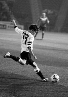 a man kicking a soccer ball on top of a field