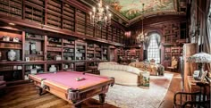 a pool table in the middle of a room with many bookshelves and couches