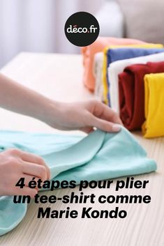 a person ironing clothes on top of a table with the words 4 etapes pour plier un tee - shirt comme marie kondo