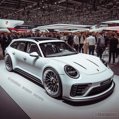 a white porsche car is on display at an auto show with people standing around it