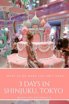 a woman sitting on top of a pink and white cake in front of a chandelier