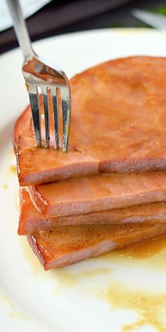 a fork is stuck into some pancakes on a plate with syrup dripping down the side