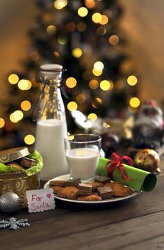 a table topped with cookies and milk next to a christmas tree