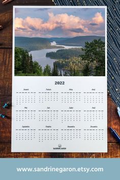 a calendar sitting on top of a wooden table next to some pens and pencils