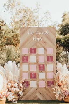 a wooden board with pink and white flowers next to potted plants on the grass