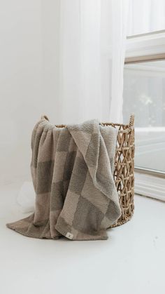 two blankets sitting on top of a white counter next to a basket with a window in the background